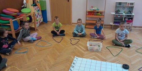 dzieci układają ze sznurowadeł figury geometryczne